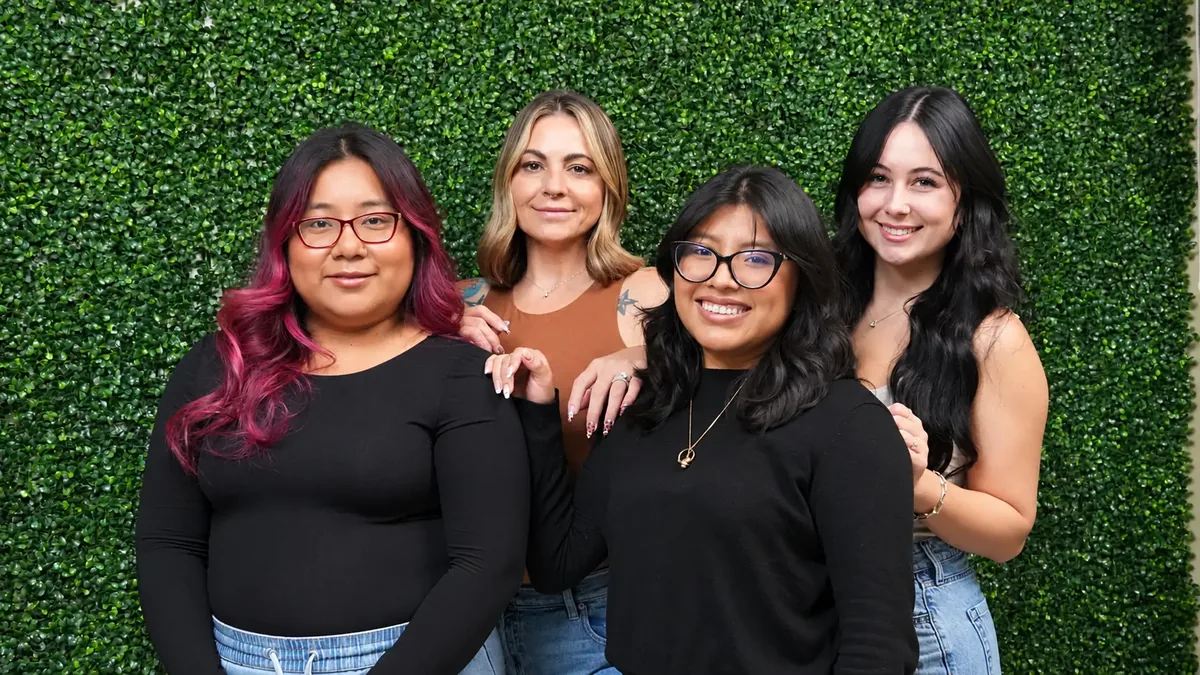 The four JM Salon stylists and esthetician together in front of the salon's leaf wall